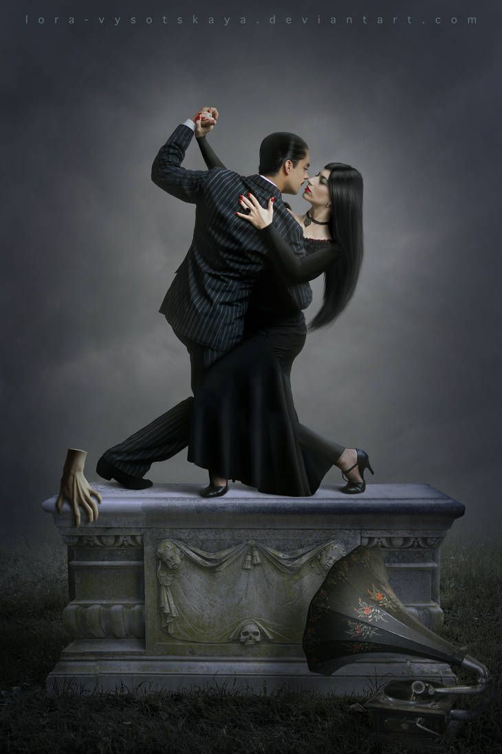 a man and woman dance on top of a statue in the dark with their arms around each other