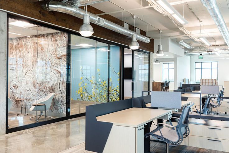 an empty office with glass walls and wooden desks in the foreground, along with two chairs on either side