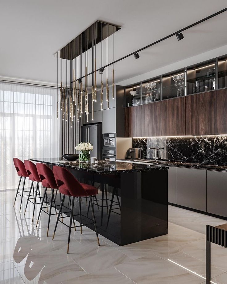 a modern kitchen with marble counter tops and red chairs