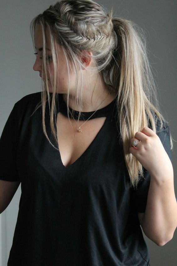 a woman with blonde hair wearing a black t - shirt and holding her hand on her hip