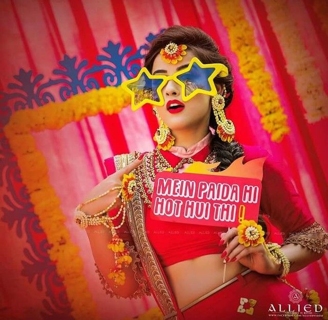 a woman in a red top and yellow glasses with flowers on her head is posing for the camera