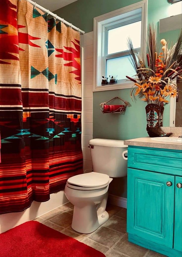 a bathroom with a toilet, sink and shower curtain covered in colorful fabric material next to a window