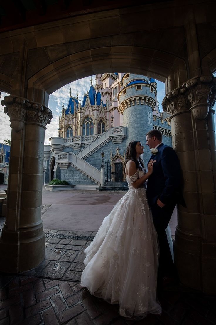 a bride and groom standing in front of a castle