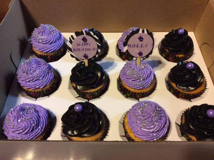 a box filled with purple and black cupcakes