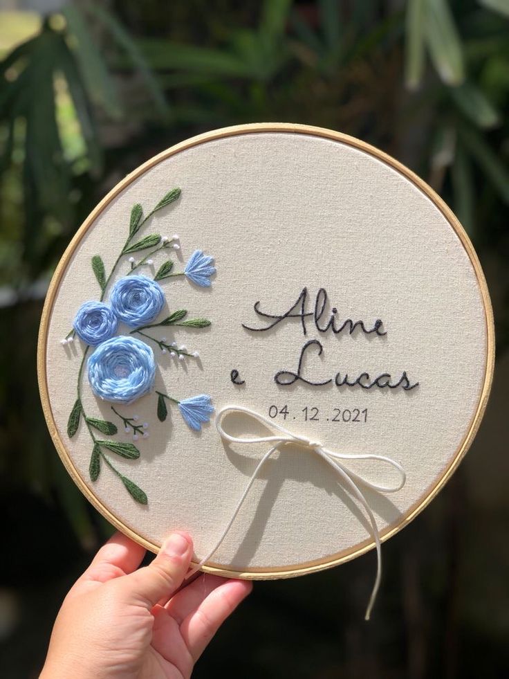 a person holding up a hand embroidered wedding gift with blue flowers on the front and back