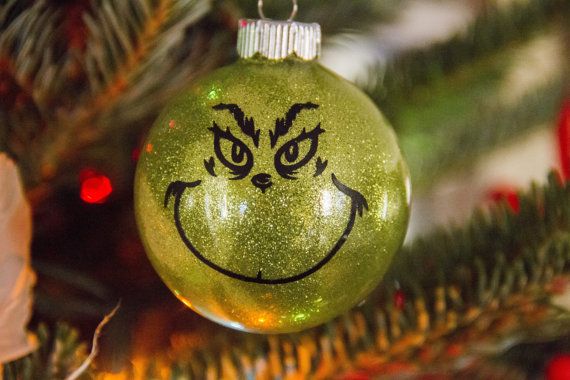 a green ornament with a grin face drawn on it hanging from a christmas tree