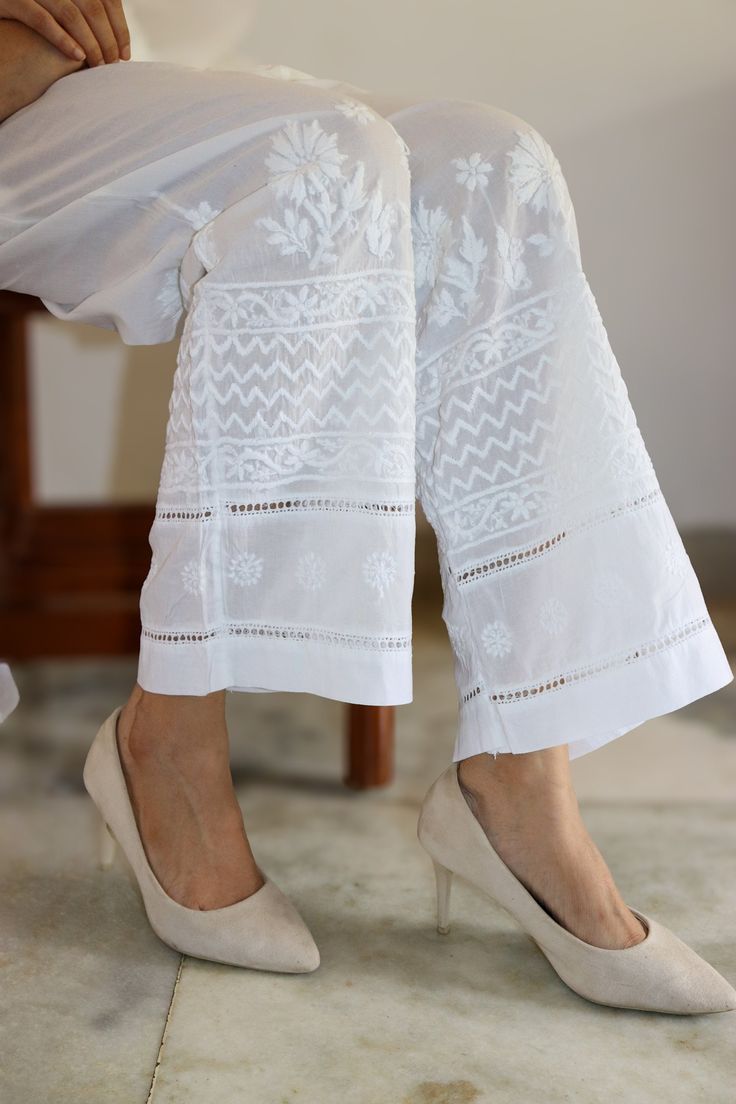 Elevate your leisure and yoga sessions with our effortlessly chic cotton pants. Crafted for comfort with a relaxed fit, these pants are adorned with vintage chikankari embroidery featuring contemporary motifs, adding a touch of artistic flair to your ensemble.  Delicate lace inserts accentuate the design, while the option of white or black hues ensures versatility in styling. Embrace relaxation in style with these timeless yet trendy pants. Comes with Pockets. Colours - White and Black Sizes - Sizes -  S -  waist stretched fits upto 40 M - waist stretched fits upto 42 L -  waist stretched fits upto 44 XL - waist stretched fits upto 46 XXL - waist stretched fits upto 48/50 prewashed. preshrunk. loris cotton pants. Straight Pants With Resham Embroidery For Spring, Spring Straight Pants With Resham Embroidery, Spring Wide Leg Bottoms With Chikankari Embroidery, White Floral Embroidery Pants For Festive Season, Festive White Pants With Floral Embroidery, Traditional Cotton Pants For Loungewear, Traditional Cotton Lounge Pants, White Chikankari Embroidery Sets With Straight Pants, Summer Cotton Pants With Chikankari Embroidery