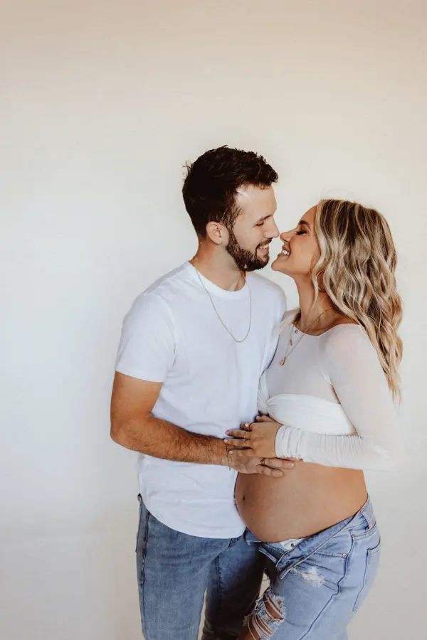 a pregnant couple kissing while standing next to each other