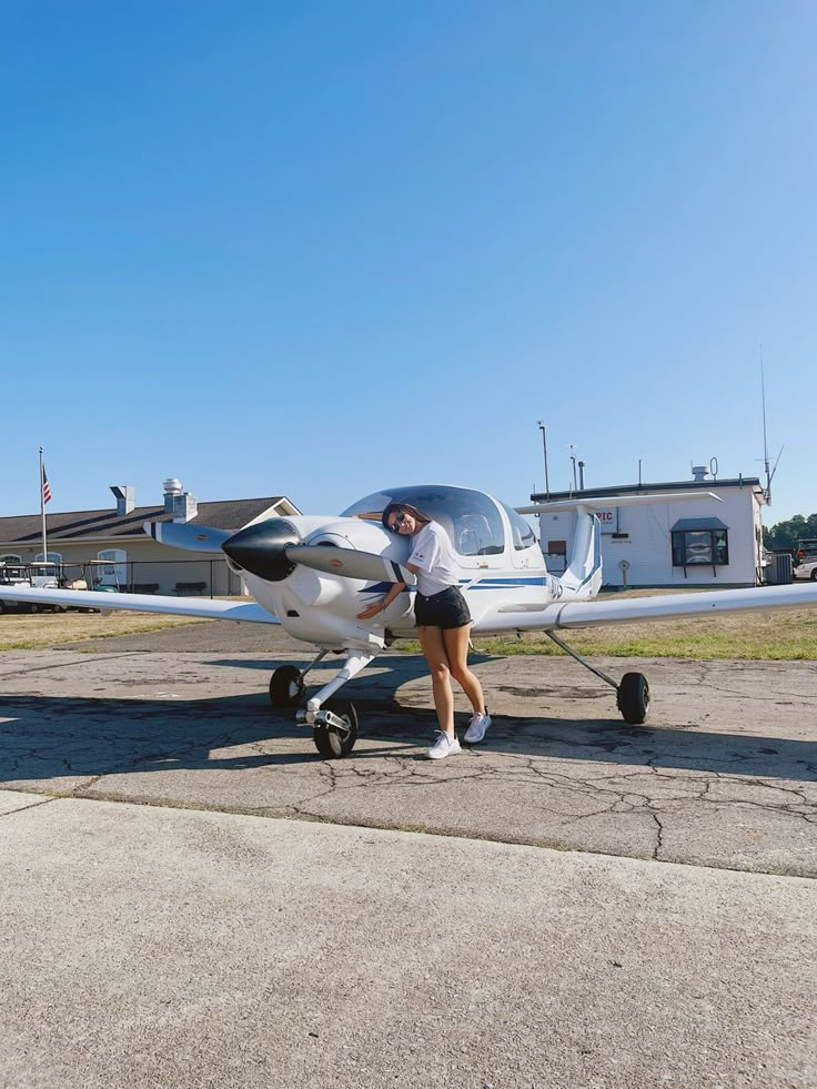 a woman standing next to an airplane on the tarmac