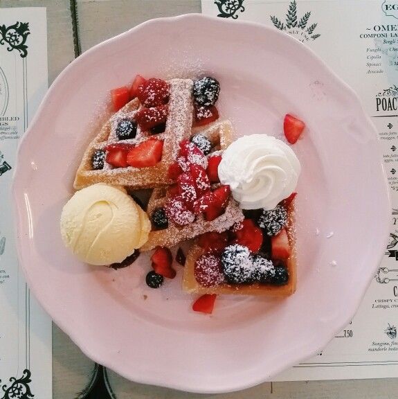 a plate with waffles, strawberries and ice cream on it sitting on a table