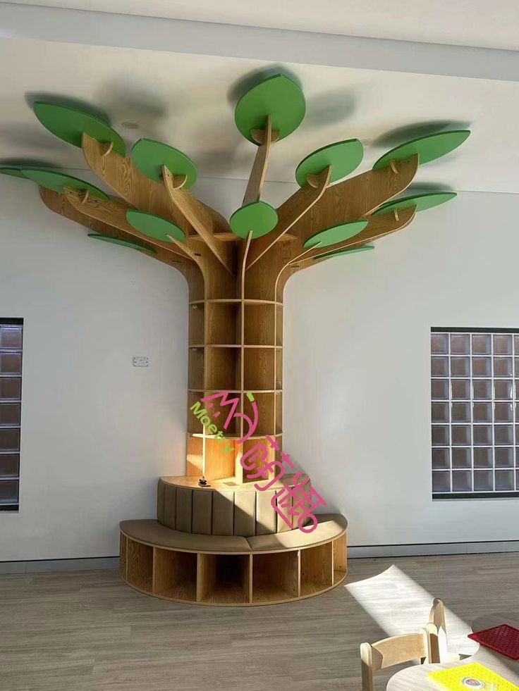 a room with a tree on the wall and various items in boxes under it,