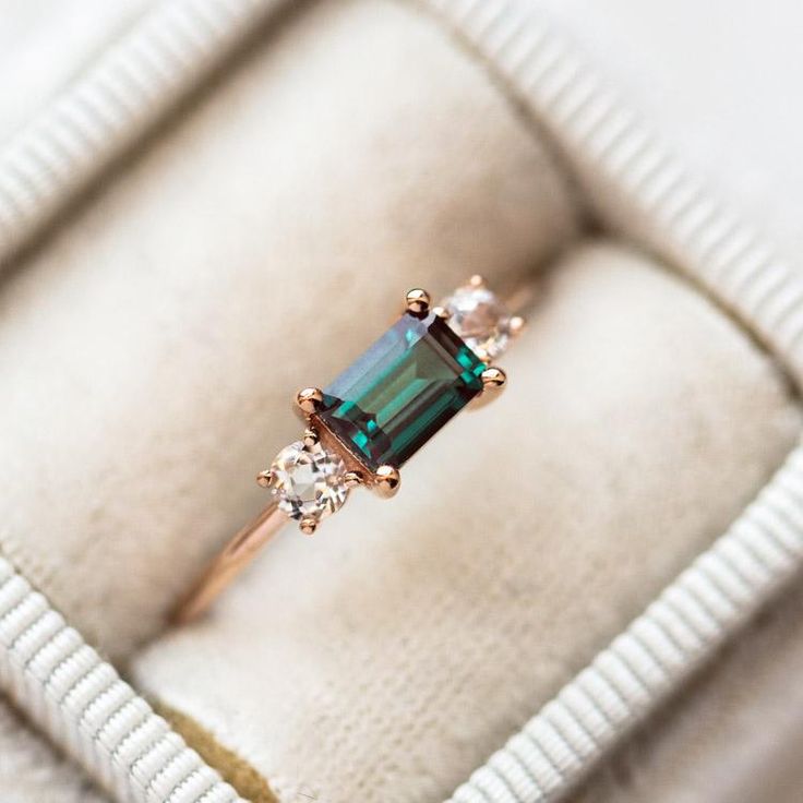 an engagement ring with a green tourmaline surrounded by three white diamonds in a box