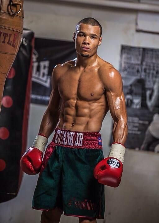 a man standing next to a punching bag in a gym wearing red boxing gloves and green shorts