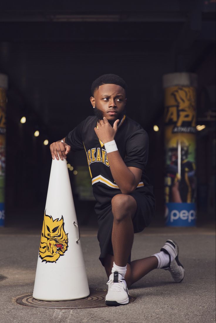 a young man sitting on top of a white cone next to a black and yellow sign