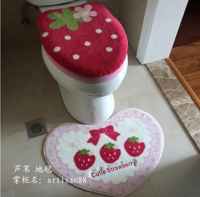 a toilet seat cover and rug in the shape of a strawberry with polka dots on it