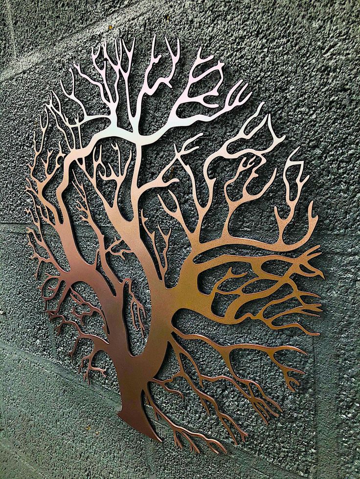 a metal tree on the side of a building with its leaves and branches cut out