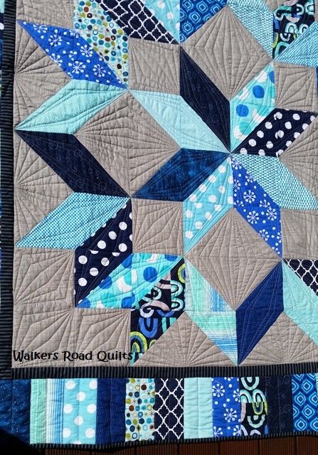 a blue and gray quilt with black, white, and blue designs on the front