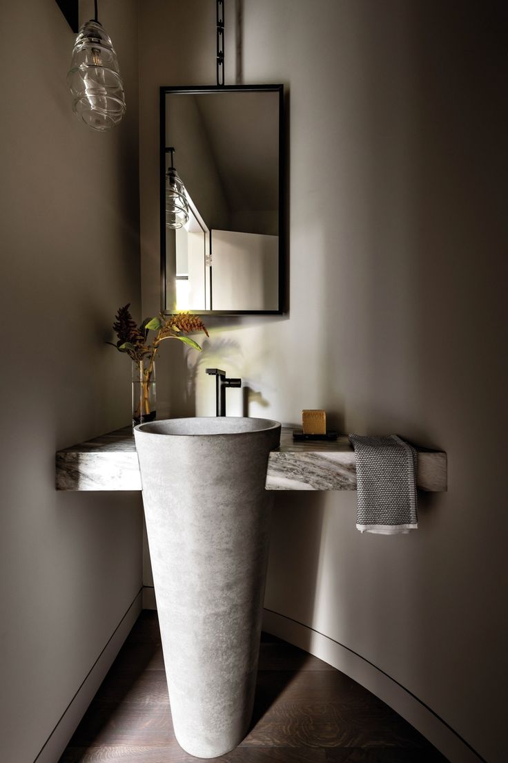 a bathroom sink sitting under a mirror next to a wall mounted faucet with a vase on it