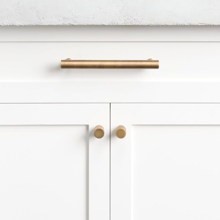 a white cabinet with brass handles and knobs