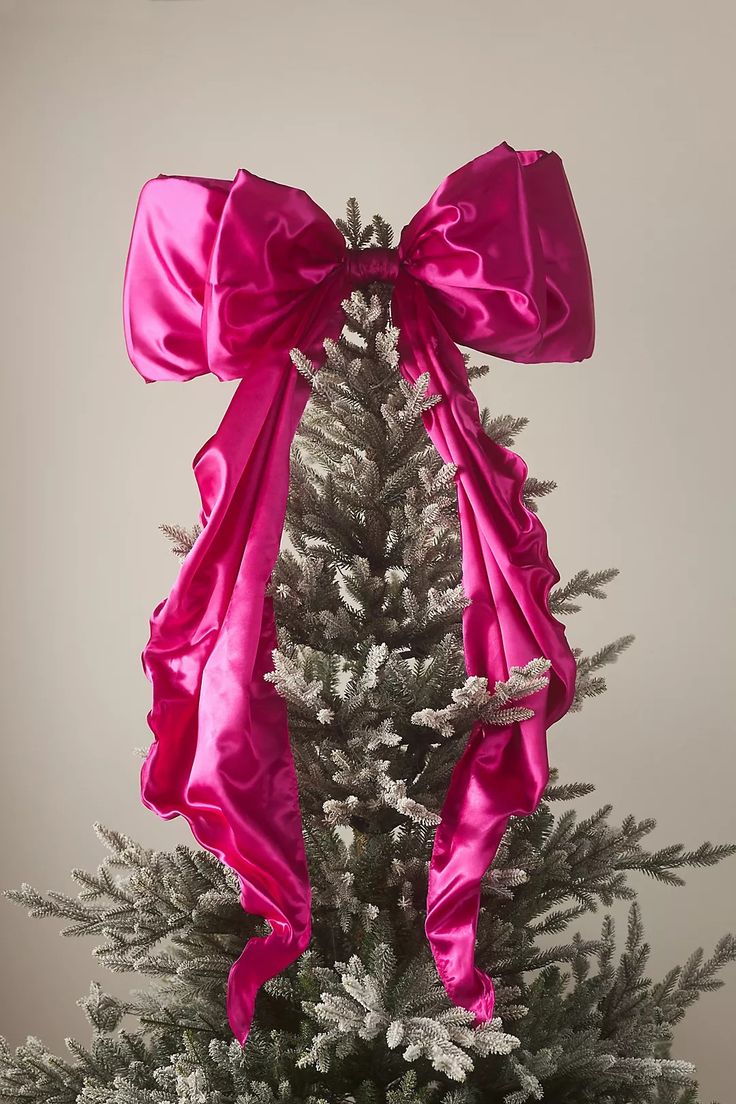 a pink bow on top of a christmas tree