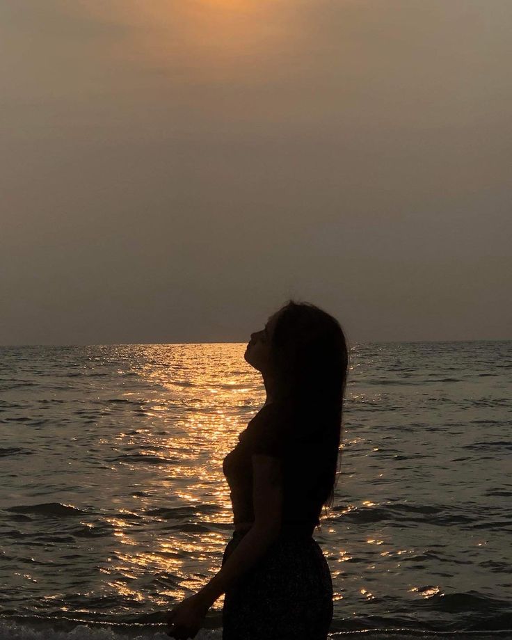 a woman standing on top of a beach next to the ocean