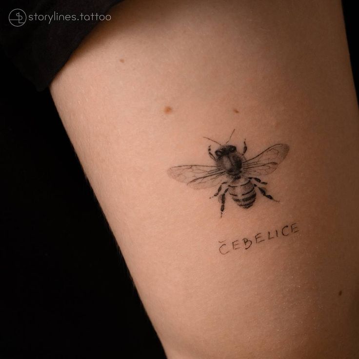 a small bee tattoo on the side of a woman's leg that reads celecitc