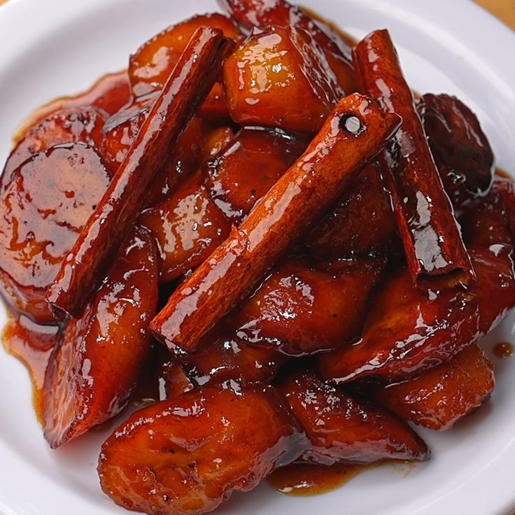 a white plate topped with cooked carrots covered in bbq sauce