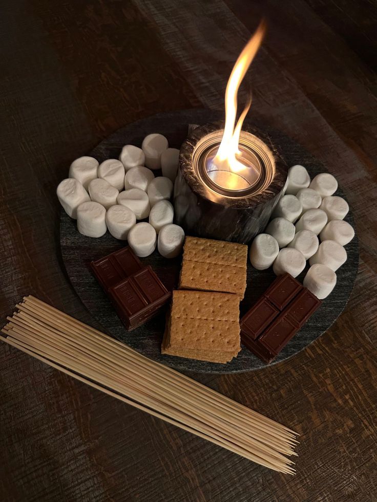 marshmallows and graham crackers on a plate with a lit candle