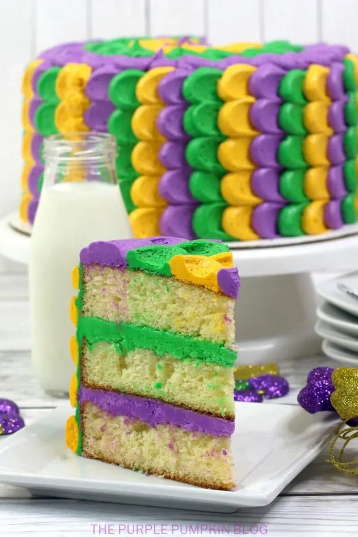 a slice of cake on a plate with purple, green and yellow icing next to it