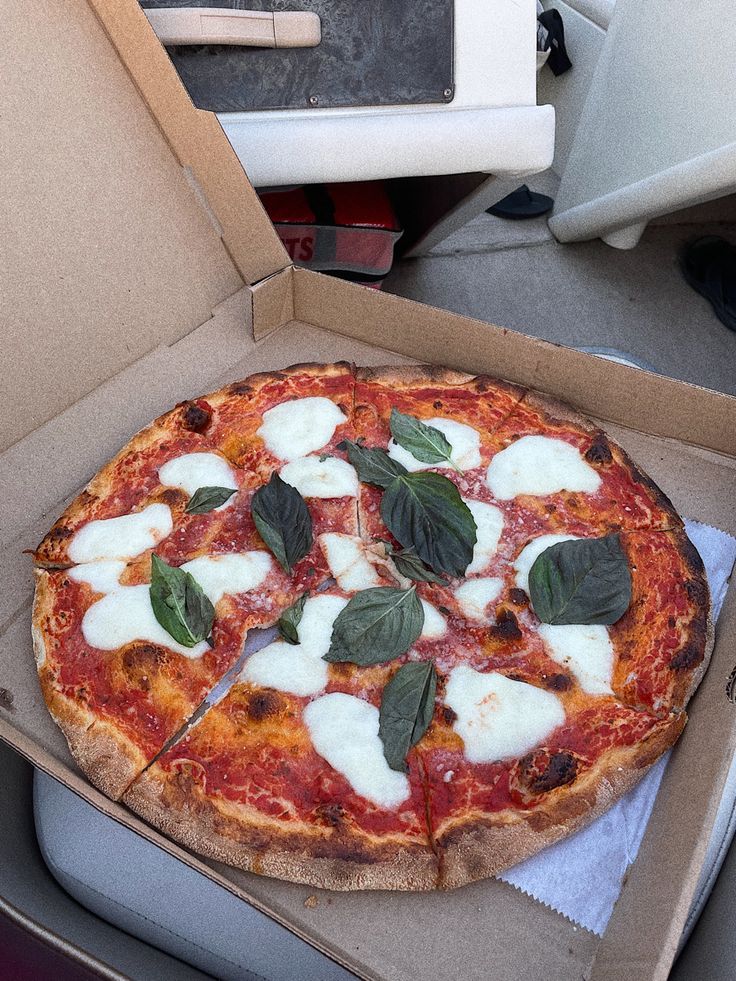 a pizza with cheese and basil on it in a box