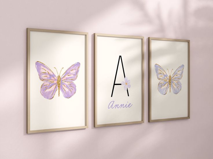 three framed art prints with the letter a and two butterflies on them, hanging against a pink wall