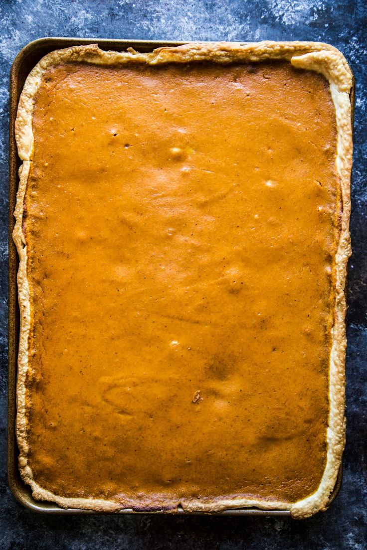 an uncooked pie crust in a baking pan on a blue surface with a spoon