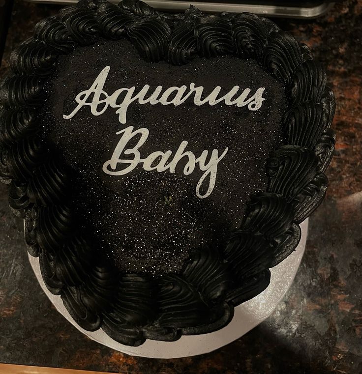 a black and white cake with the words aquarius baby written on it's side