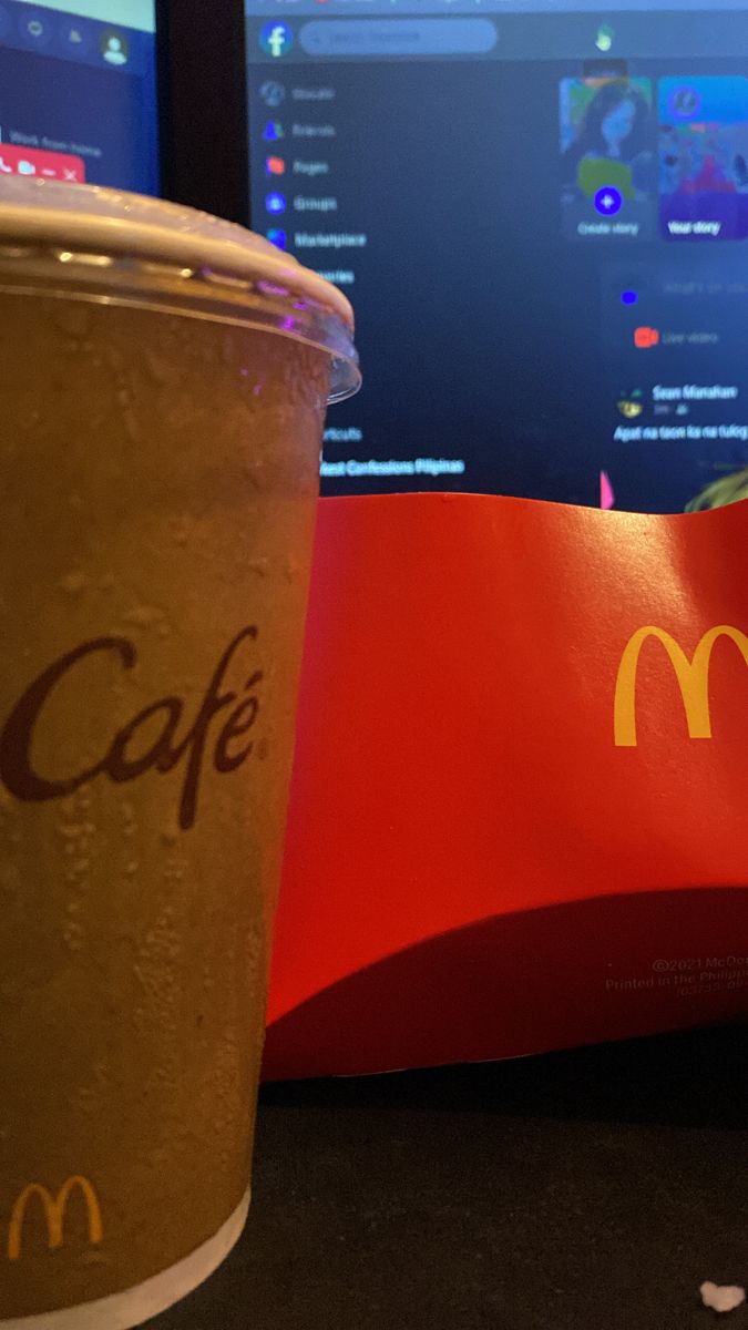 a mcdonald's coffee cup next to a computer monitor with the mac logo on it