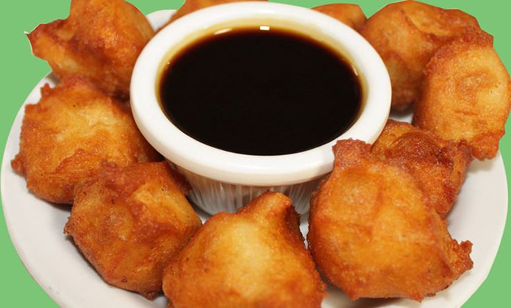 some fried food on a white plate with dipping sauce in the middle and green background