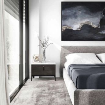 an image of a bedroom setting with white walls and grey carpeted flooring that has a painting on the wall above the bed