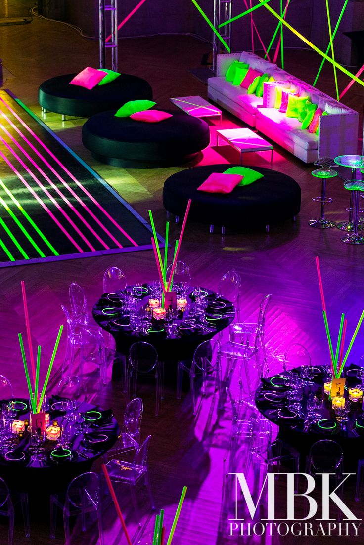 a room filled with tables and chairs covered in neon lights at a party or event