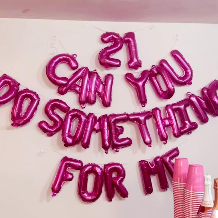 some pink cups and balloons that say 21st birthday for my sister on the wall behind them