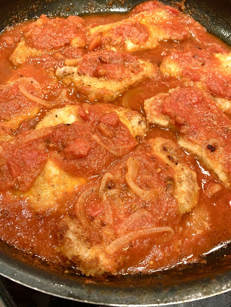 a skillet filled with meat and tomato sauce on top of a stovetop burner