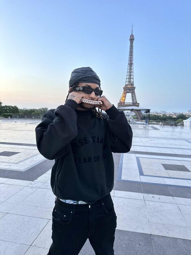 a man standing in front of the eiffel tower with sunglasses on his face