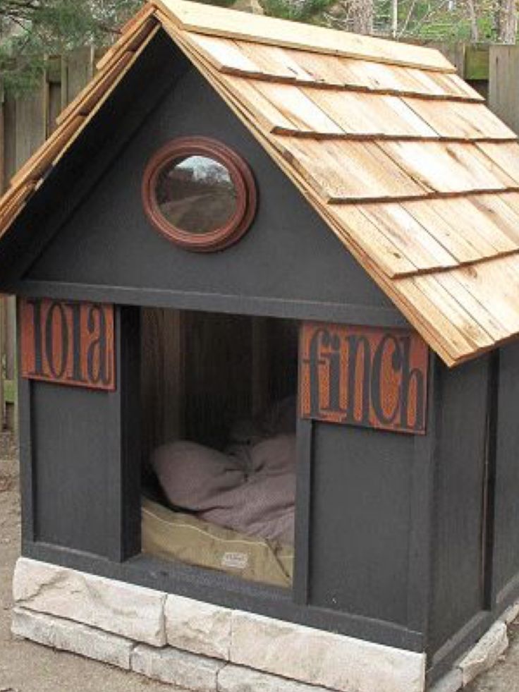 a dog house made out of wood with a bed in the middle and a window on top