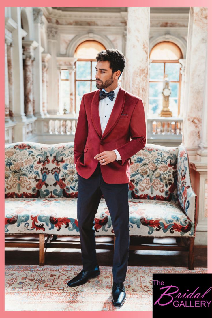 a man in a red tuxedo standing next to a couch