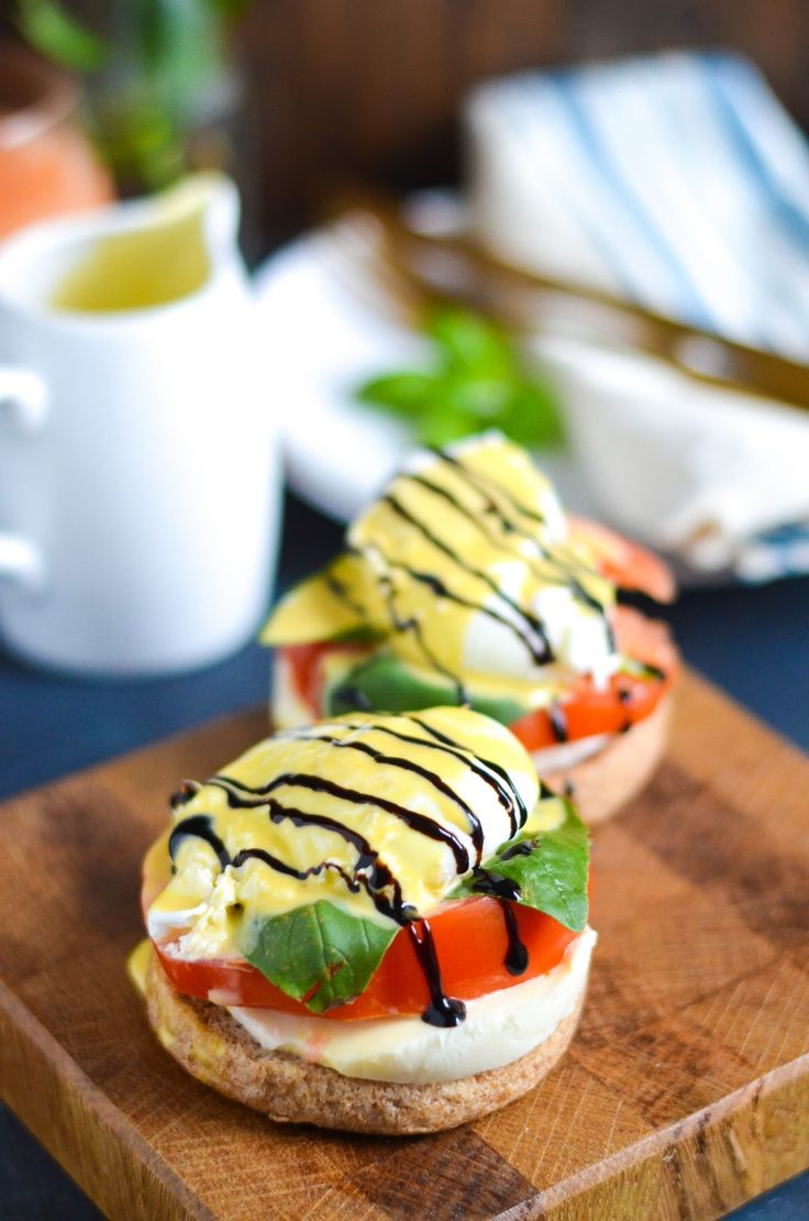 two sandwiches with cream cheese, tomatoes and lettuce sitting on a cutting board