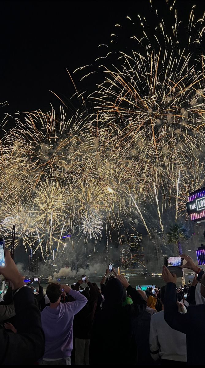 people are taking pictures with their cell phones as fireworks go off in the sky