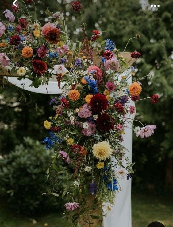 a bunch of flowers that are on top of a chair in front of some trees