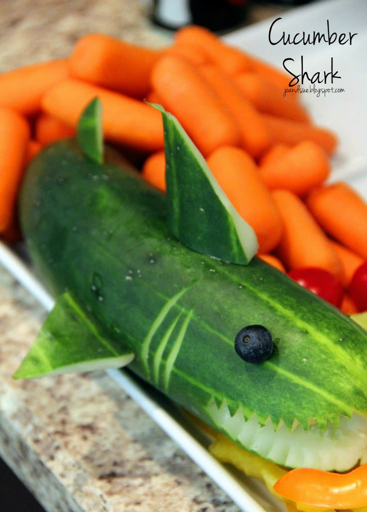 a close up of a plate of food with carrots and cucumber shark