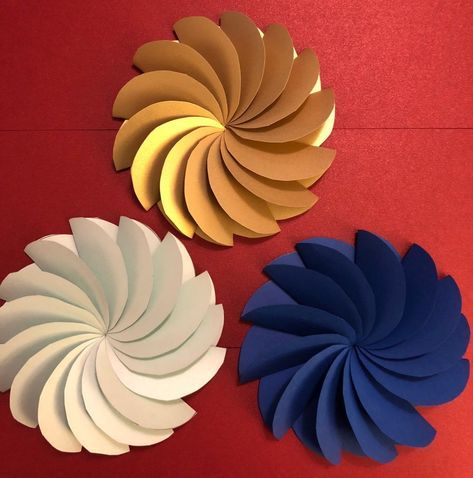 three different colored paper flowers on a red surface