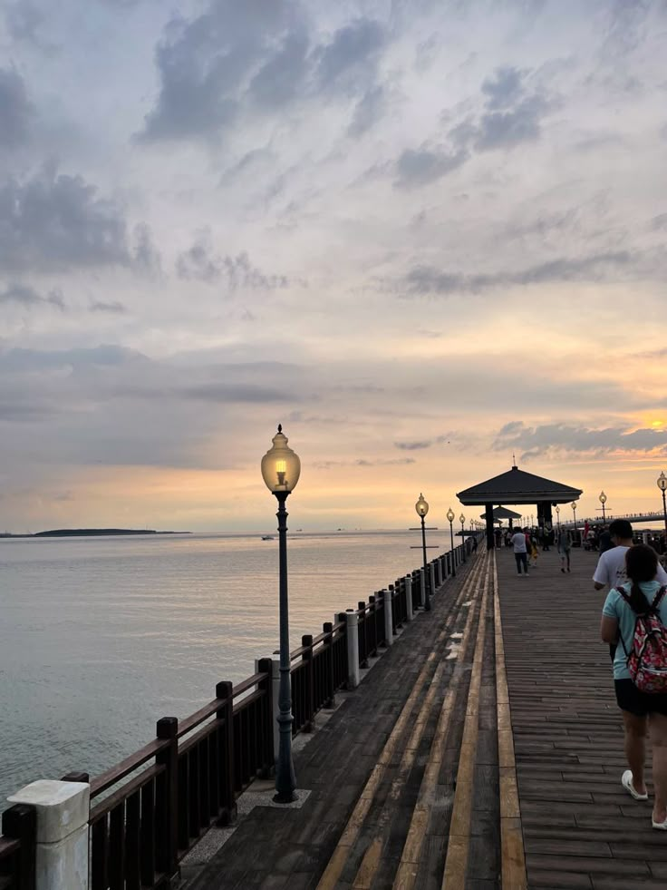 two people walking on a pier near the ocean