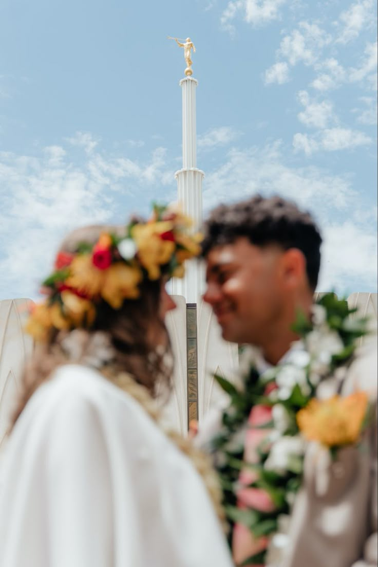 a man and woman standing next to each other in front of a tall white cross