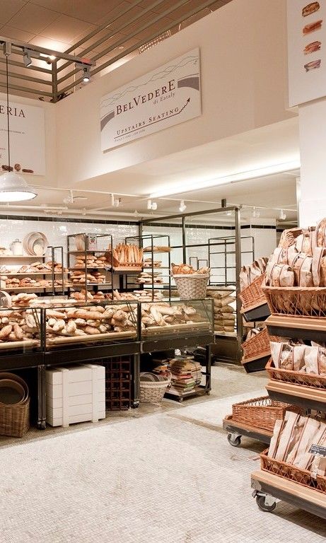 a bakery filled with lots of breads and pastries next to baskets on the floor